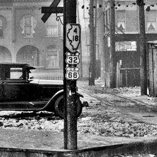 Route 66 shield on Ogden Ave 1930 black and white. car by a light post with shields of US 66, US 32, IL 4 and IL 18