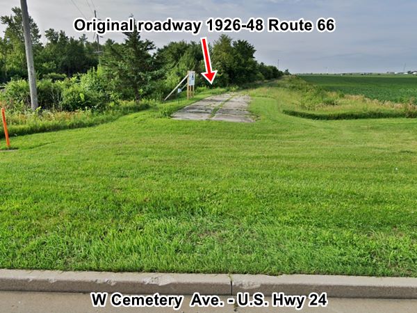 Abandoned 1926-48 Route 66 roadbed in Chenoa IL color, current view of a cracked concrete roadbed separated from a modern highway by a gap filled with grass, field to the right, trees to the left