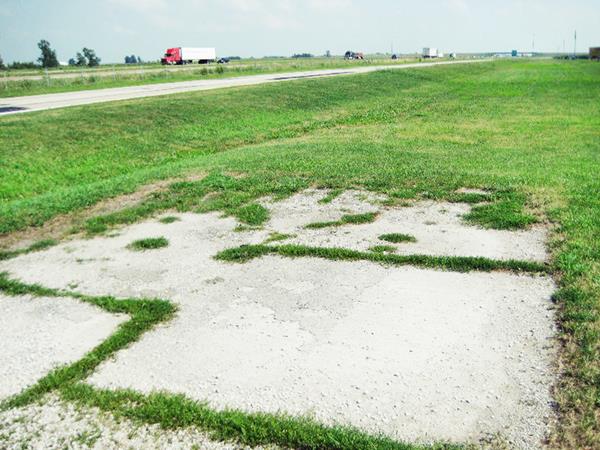 cracked concrete with weeds growing in the cracks, on the shoulder of Route 66, the original roadbed