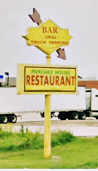 yellow diamond shaped sign with red arrow by roadside