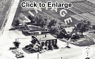 aerial view of Rodino Square and US 66, 1965 Black and white, 1965, aerial view railroad and old US 66 to the left, on the corner is a 2 story bldg, cars, some houses and trees, IL-116 runs across bottom