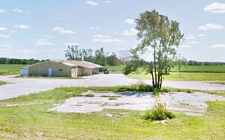 Sands Motel ruins, gable roof, single story behind an empty lot with concrete drive