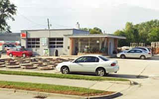 color, box shaped former gas station, with 2 service bays and corner office with angled plate glass, a U-HAUL store