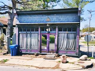Old store front painted violet with windows on the sides and door in the middle seen from US66