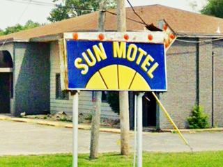 blue and yellow neon sign with words Sun Motel on it