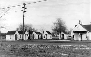 Sunset Inn and Cabins black and white, 1940s small cabins, by highway, gas station to the right