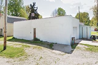 white box-shaped concrete block building with walled service bays on a corner