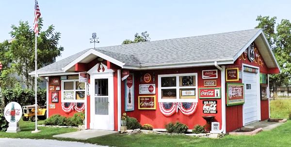 color, red walled cottage with gable roof, American Flag, Coca Cola and US 66 signs and shields