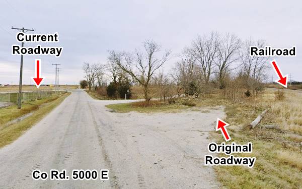 road by a railroad and old US66 alignment roadbed on the right, covered by shrubs and trees