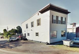 two story narrow building with flat roof, wood siding exterior walls