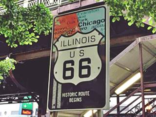Begins sign HISTORIC ROUTE 66 BEGINS sign: US 66 shield, orange, and light blue, and town names around Chicago