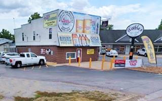 color, 2019 bldg. 2 stories, US 66 runs in front, cars parked, oval shaped sign