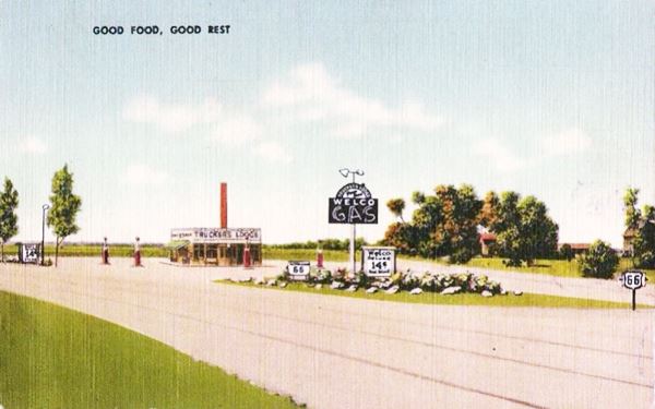 color postcard painted, box shaped gas station at fork in US66 Highway. GOOD FOOD GOOD REST written on it