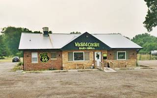 color, view of cross gable roof, one story building by US 66 a bar