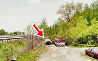 overgrown dead end, cracked concrete paving, old abandoned cars and trees