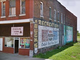 fading painted advertisements of Pepsi and Mountain Dew on a red-brick wall