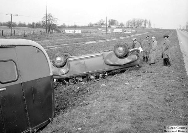 black and white photograph of a vehicle and trailers, in an accident