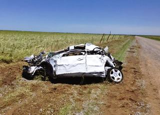 car mauled by a tornado white car crumpled and destroyed on the side of a road by a field