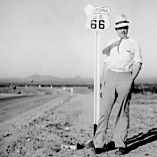 Jack Rittenhouse, 1941 black and white: Mr. Jack Rittenhouse by a Route 66 shield sign, in the Mojave Desert, US 66 to the left, 1941