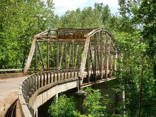 1923 Bridge steel bridge on a narrow highway surrounded by a forest