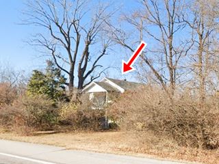 two-floor gable roof building partly concealed by trees next to Route 66, in fall