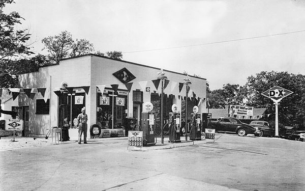 black and white 1940s photo gas station, cars and attendant