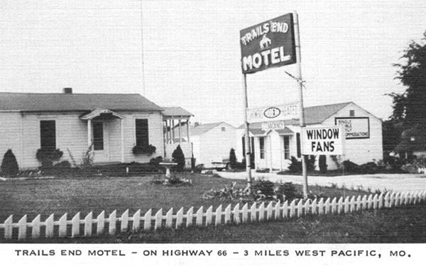 black and white picture gable roof cabins and office of a motel, with neon sign