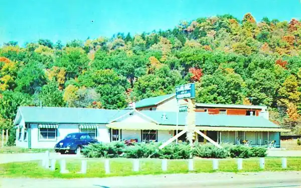 1940s car and motel with woods beyond