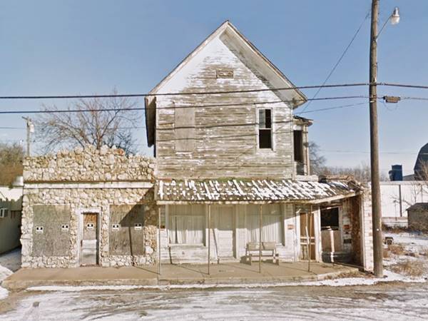 old abandoned stone faced store and a two story wood faced building