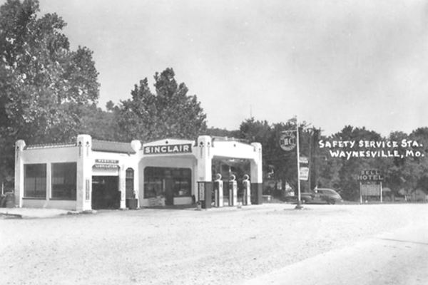 black and white photo of a Sinclair gas station, highway and car, taken in the 1930s