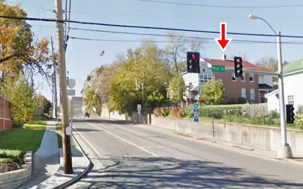 gable roof brick home (right), white bluffs with trees, Route 66 runs at the foot of cliff and house, 2021