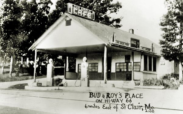 gable roof canopy, gas pumps and office of gas station in black and white 1930s photo