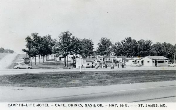vintage 1950s black and white postcard, D-X station, cabins, car, trees and highway