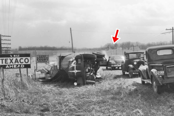 1940s black and white photo of a crash, with Route 66, cars, truck lying on shoulder and signs
