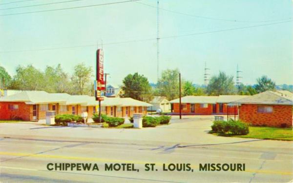 motel units around courtyard with gable roofs and a neon sign in a color vintage postcard