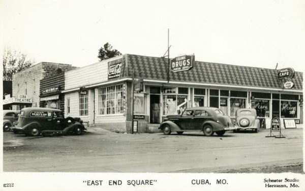 black and white 1930s postcard, drug store, cafe, cars and movie theater