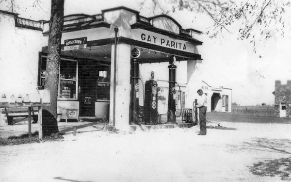 black and white photo of canopy, pumps and filling station with man, c.1930s
