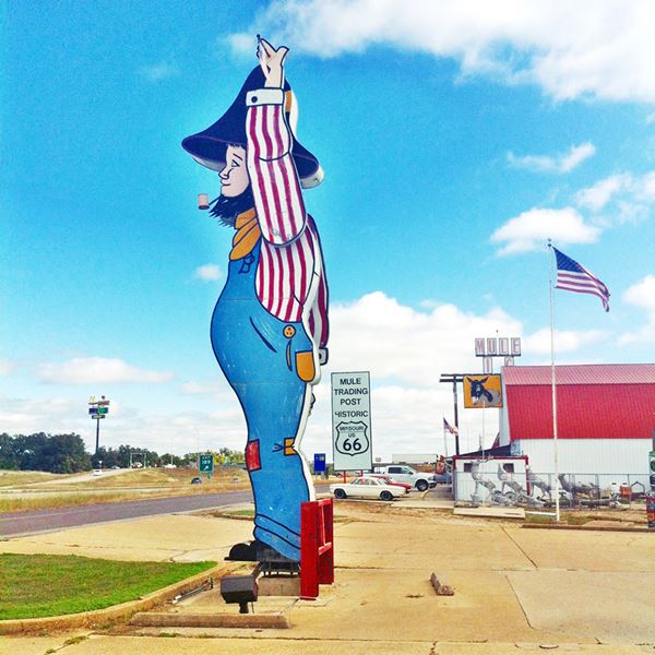 sign shaped like a giant hillbilly next to Route 66