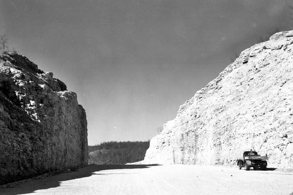 black and white photo, truck on dirt roadbed between high rock walls