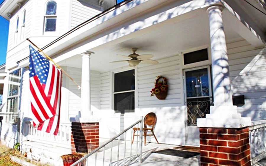 white wood siding house with american flag on its porch