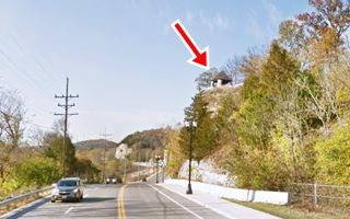 small building on the top of a cliff overlooking the highway, seen from Route 66 below