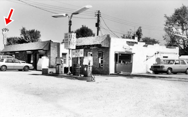 black and white 1993 view of a cafe and gas station, pumps, key shaped neon sign and cars