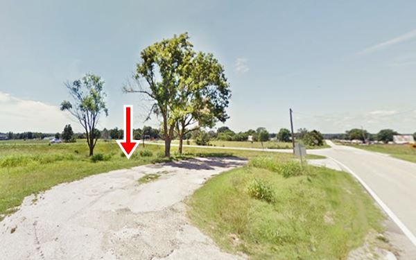 gravel driveway, trees and grass next to US66. site of former gas station
