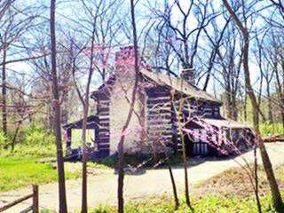 William Long Cabin 1821 log cabin in a wooded area, flowering trees in early spring
