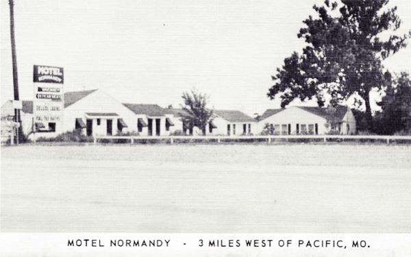 black and white postcard from the 1940s of a long, one-story gable roofed complex by Route 66