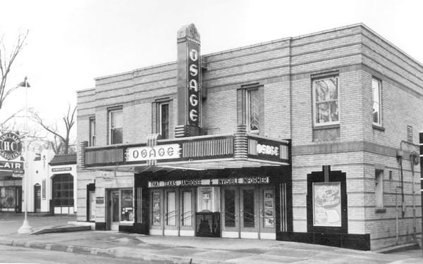 black and white 1940s photo of a single floor brick building, a movie theater