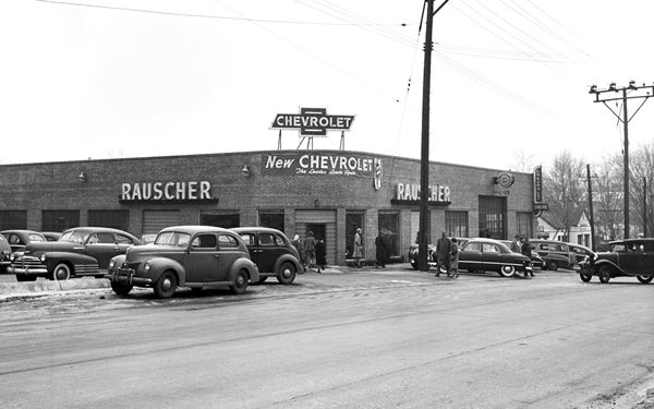 black and white 1949 photo of a Chevrolet auto dealer, with cars, brick building and US66