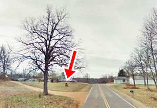 marker on lawn by Route 66, trees and home in the background