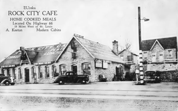 black and white photo from 1930s stone gable roof buildings and cars, a cafe