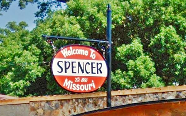 red and white sign with black and white letters saying " Welcome to Spencer Missouri Est. 1886"